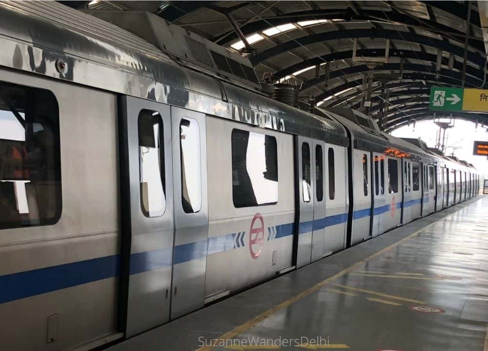 A blue line Delhi metro train waiting at a station - the best way to travel the distance between New Delhi and Old Delhi