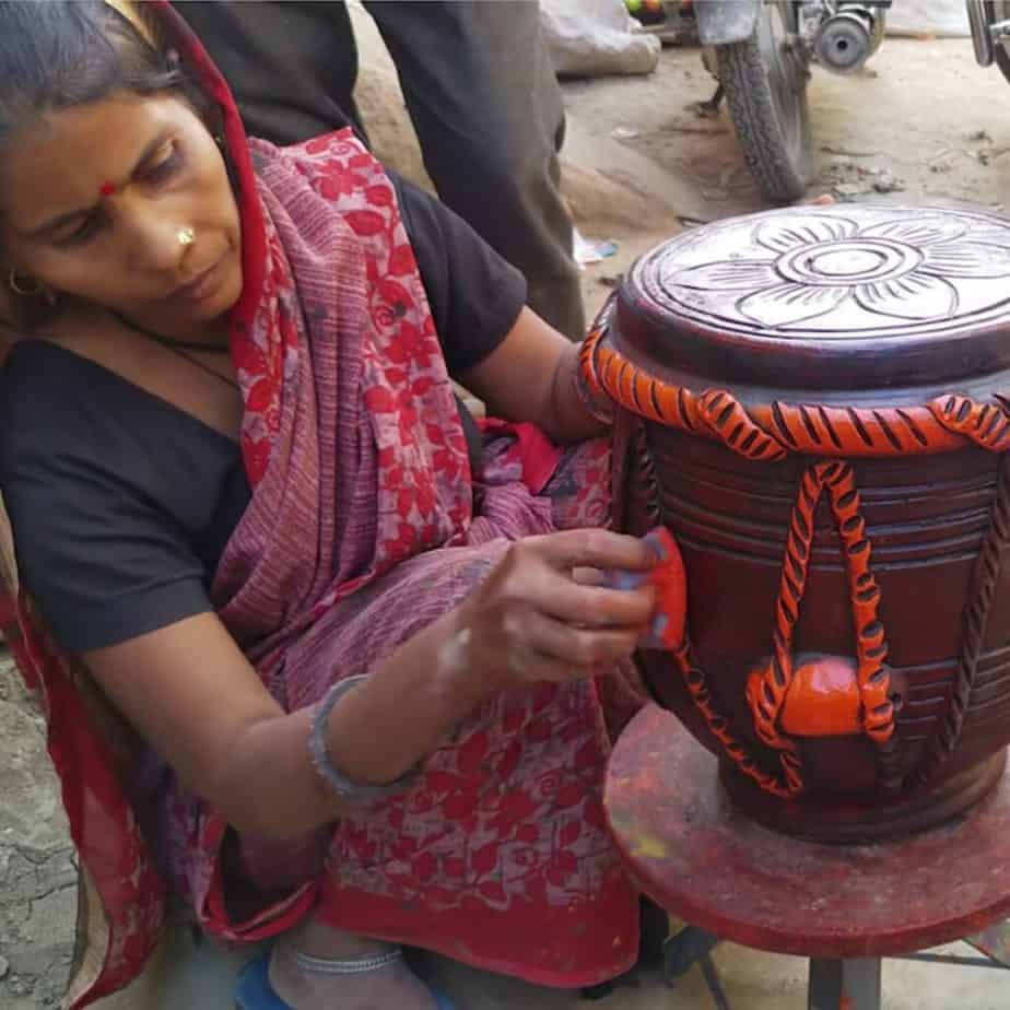 A woman sitting on the ground an hand painting a cermic item in Kumhar Colony, Delhi