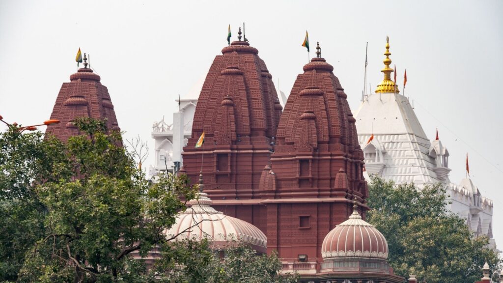 Red sandstone spires and white spires behind taken from a distance/21 Famous and Unique Temples in Delhi