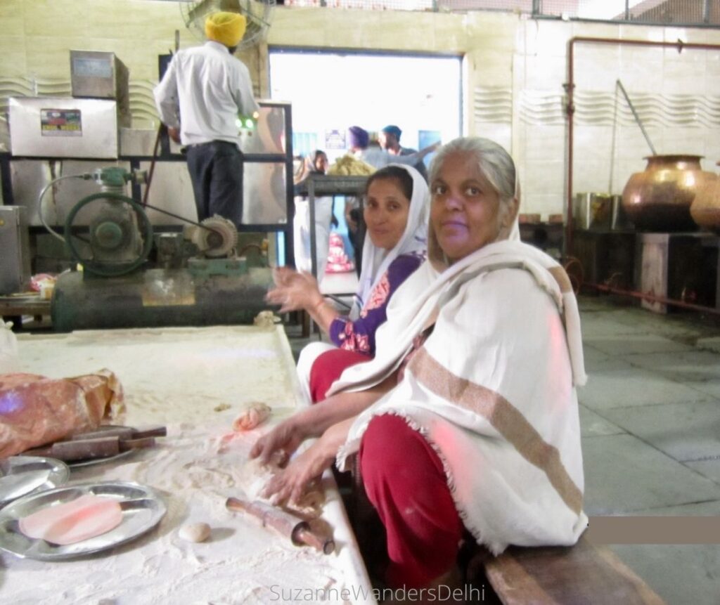 Two Indian women sitting and preparing rotis in Gurudwara Sis Ganj kitchen - helping in a guruduwara is one of the most special ways to get cultural in Delhi