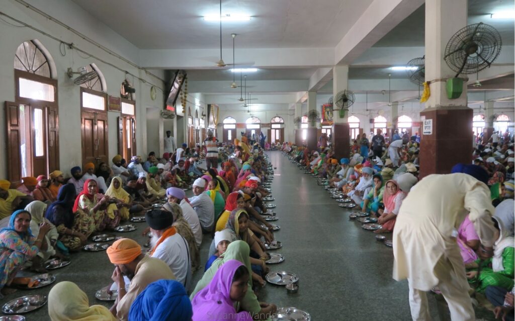 Rows of people sitting in the langar hall at the Golden Temple in Amritsar