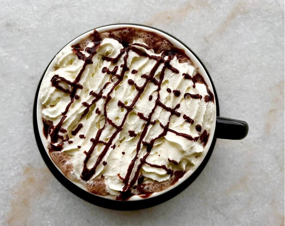 Cup of hot chocolate with whipped cream and chocolate sauce