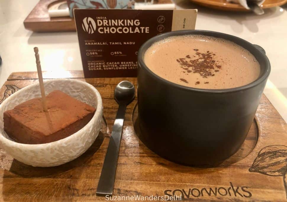 cup of hot chocolate with chocolate marshmallow in bowl on the side on wooden serving board at Savorworks in Delhi