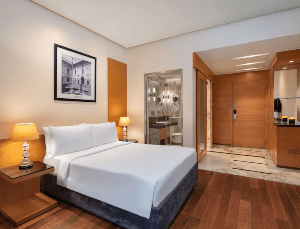 A superior room with white sheets and brown wooden floors at the Radisson Blu Marina, one of the best hotels to suit every budget in Delhi