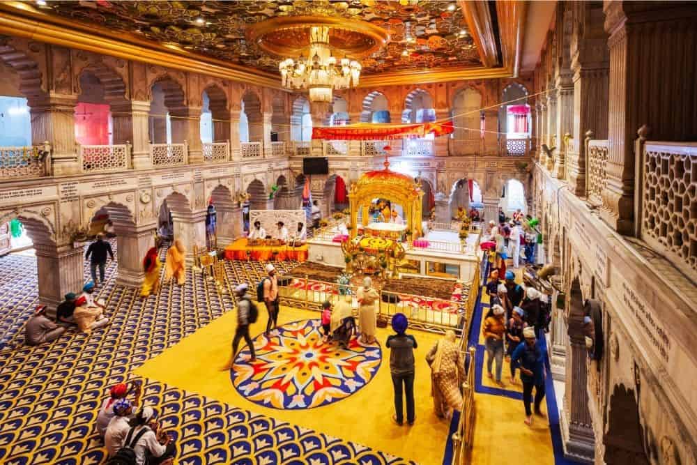 The interior of Gurudwara Sis Ganj Sahib showing a beautiful, carpeted prayer hall with elaborately decorated ceiling / 21 Famous and Unique Temples in Delhi