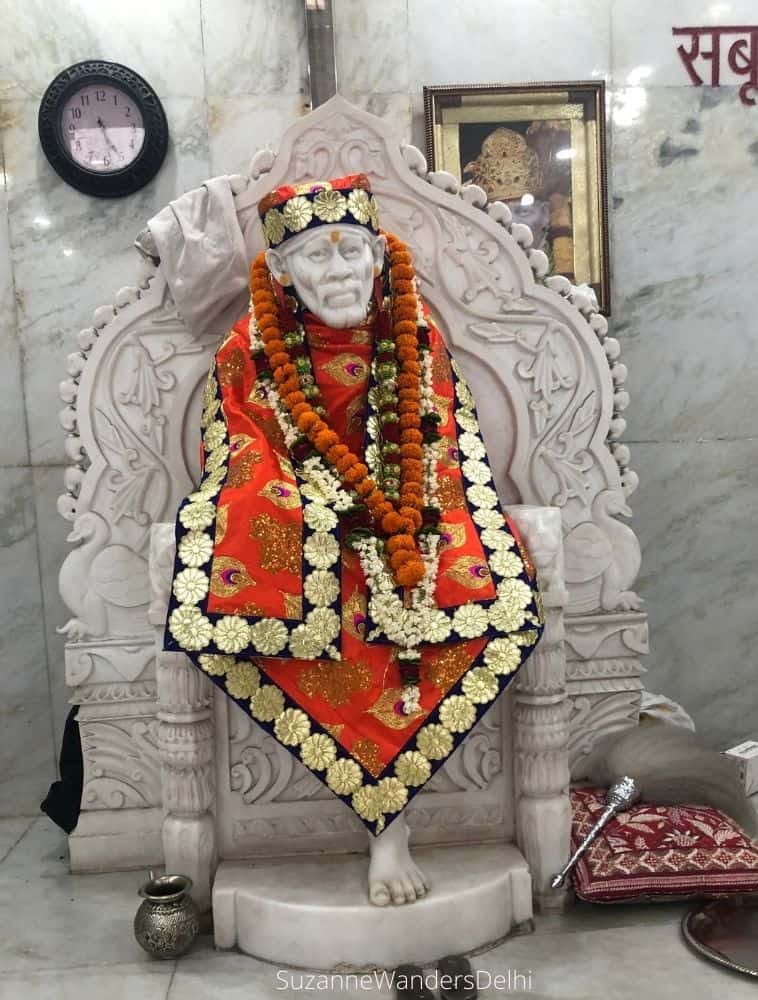 Sai Baba idol in white marble enrobed in orange and gold and marigolds at the Valmiki temple in Khan Market