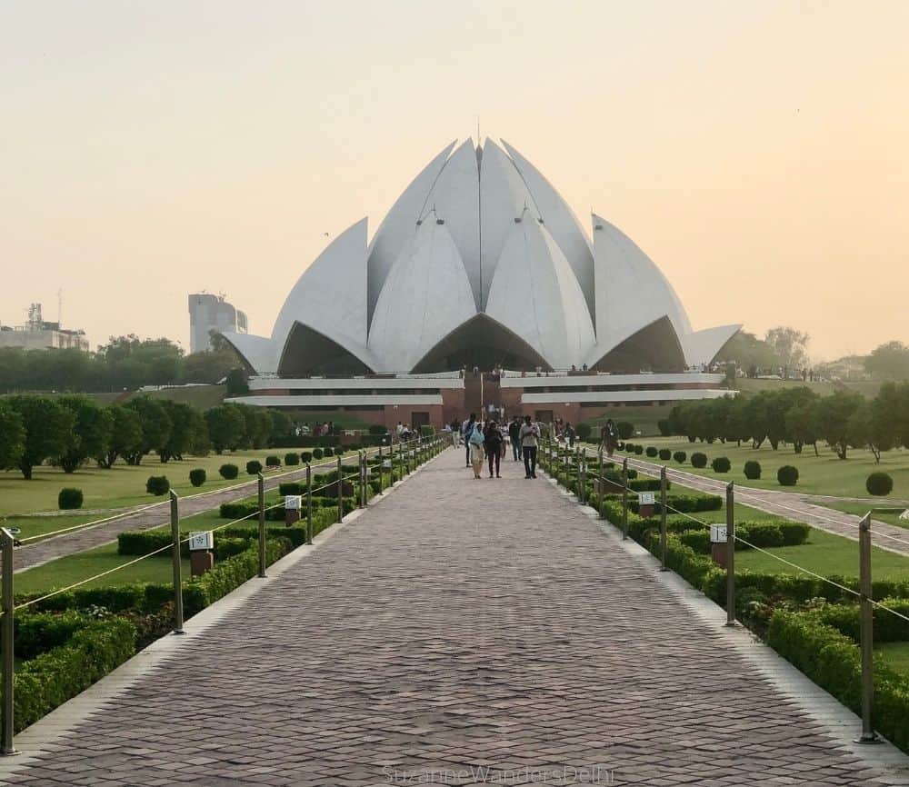 Exterior view of Lotus Temple with brick walkway flanked by green gardens on each side