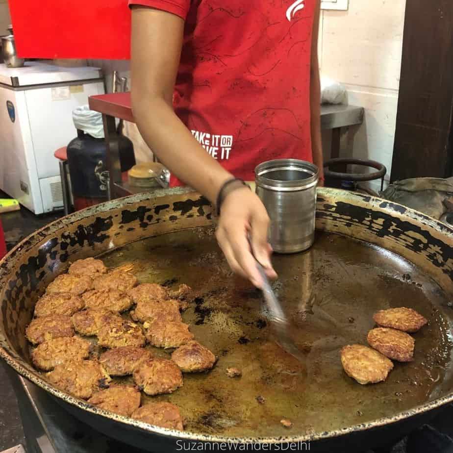 Mutton patties cooking on a giant round pan and the chef flipping them / 3 Markets for Street Food that Aren't in Old Delhi