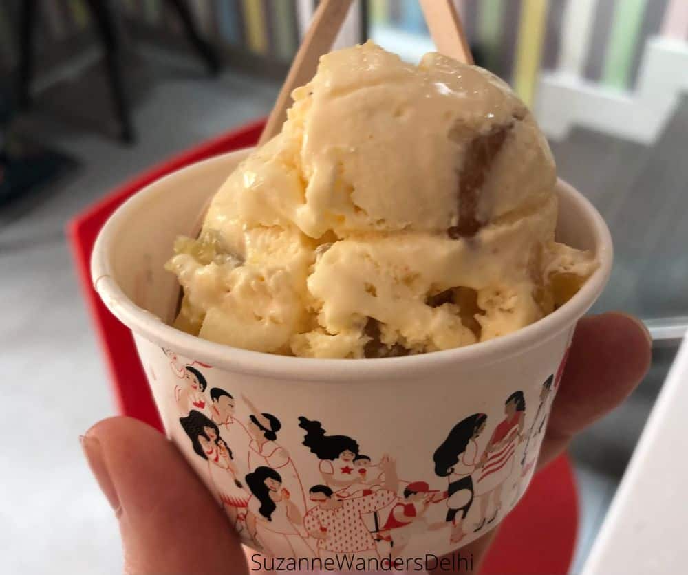 A Nirula's cup filled with Pineapple Chili ice cream being held by onehand