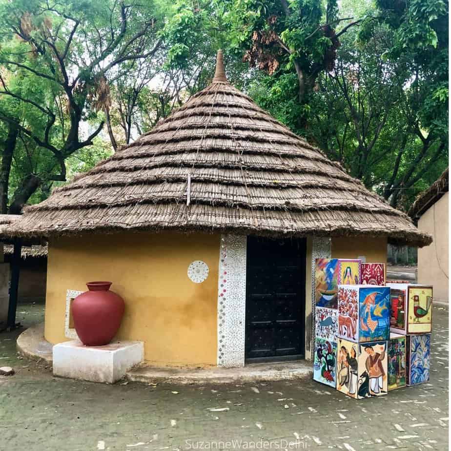 Round, yellow village house with thatch roof at National Crafts Museum, one of the best off the beaten path sites in Delhi