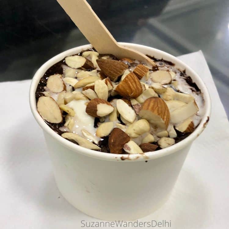 A white cup filled with ice cream and covered in almonds and chocolate sauce at Classic Ice Cream Cafe, the best family place for ice cream in Delhi