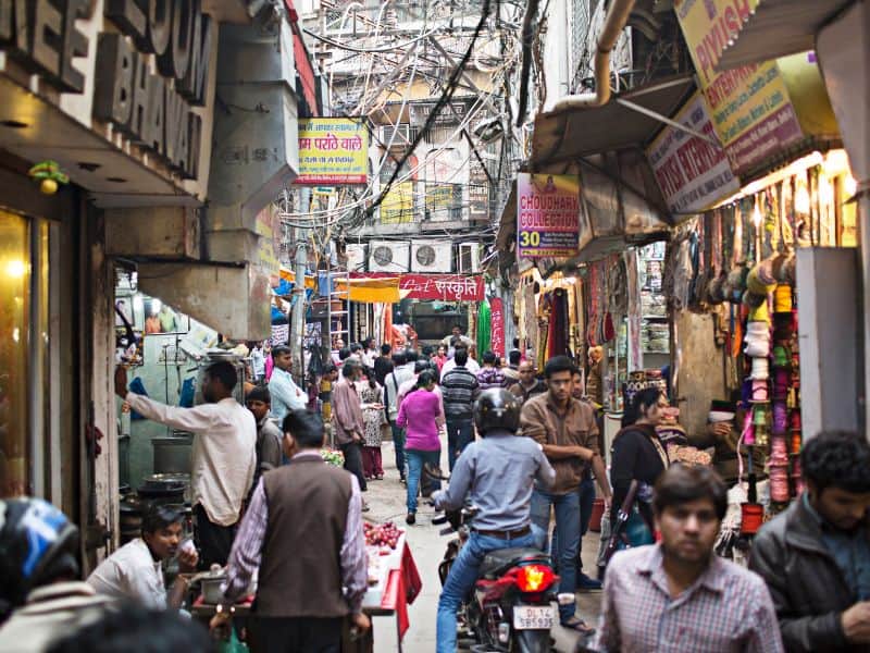 Old Delhi street with jumble of overhead wires and pedestrians and motorcyles