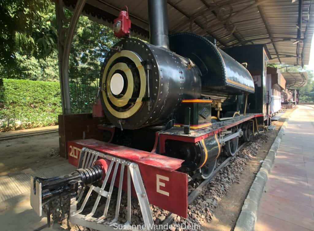 a red and black steam locomotive oudoors at the National Railway Museum in Delhi
