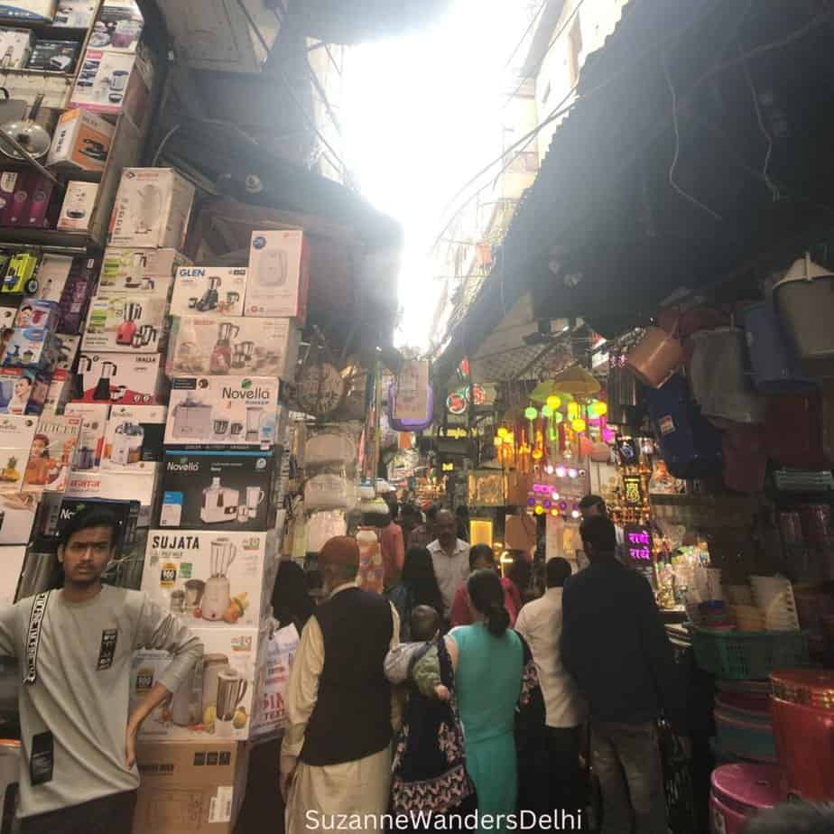 A congested market lane with shoppers and displays of kitchen small appliances in Sadar Market, Old Delhi, one of the best and cheapest markets in Delhi