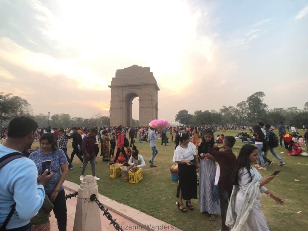 India Gate in Delhi with lawns full of people and man selling cotton candy, a great place to visit on a day in Delhi with kids