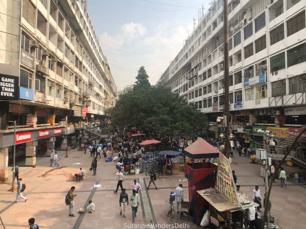 The main lane at outdoor Nehru Place Market, flanked by buildings on either side and trees in the middle.