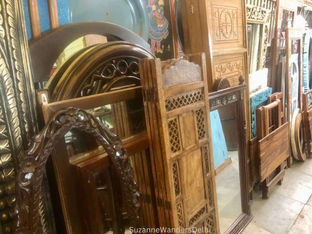 A selection of mirrors and wooden screens propped up against a wall in Amar Colony Furniture Market