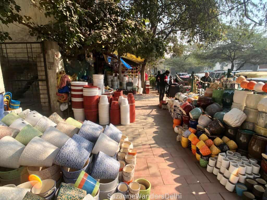Looking down Hauz Rani pottery market and a large selection of colourful pots for plants on both sides of the sidewalk