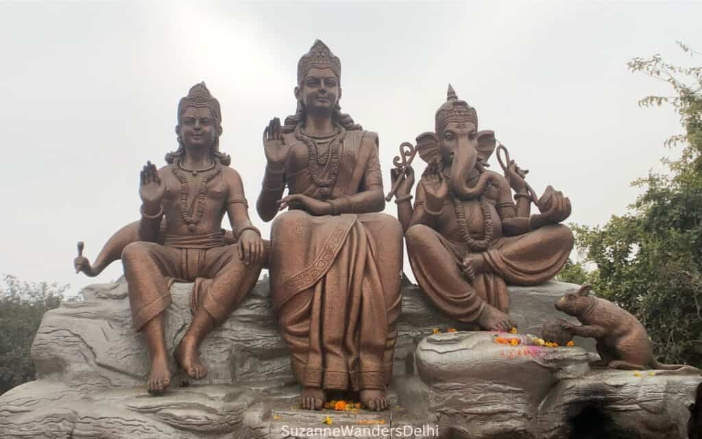 Bronze statue of Lord Ganesha, Parvati and Kartikeya on rocks outdoors at the Shivaji Murti