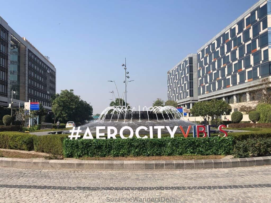 the sign and fountain at Aerocity, flanked by hotels