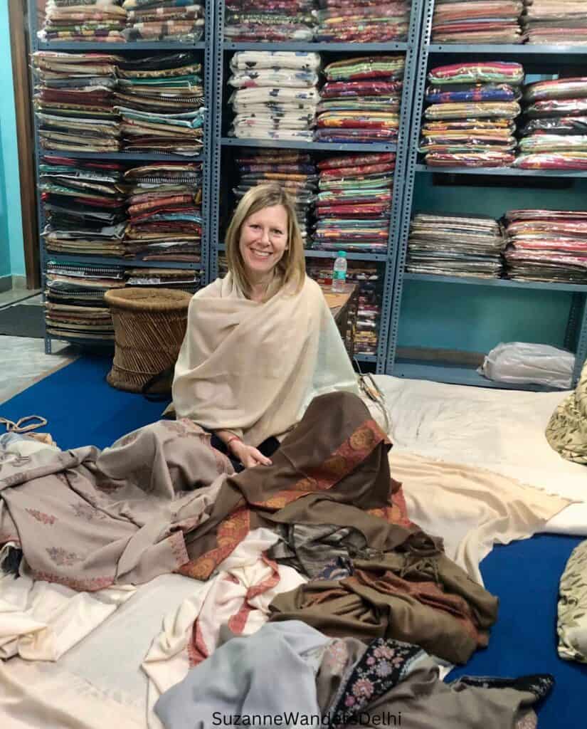 the author draped in a pashmina sitting on the floor of a wholesaler with pashminas all around