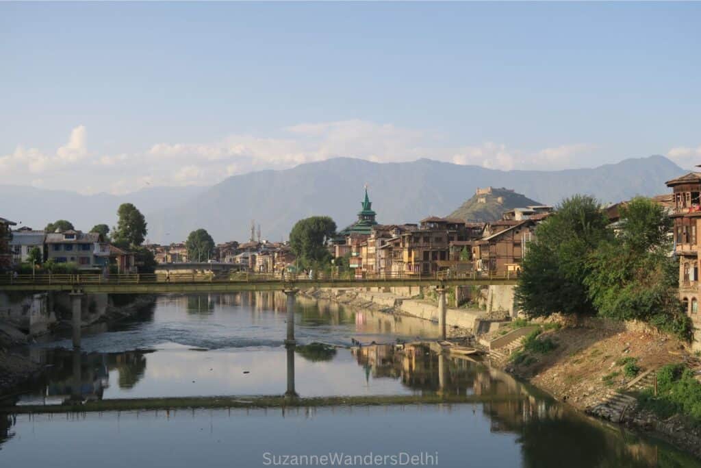 view of river in Srinigar in Kashmir with bridge and mountains in background
