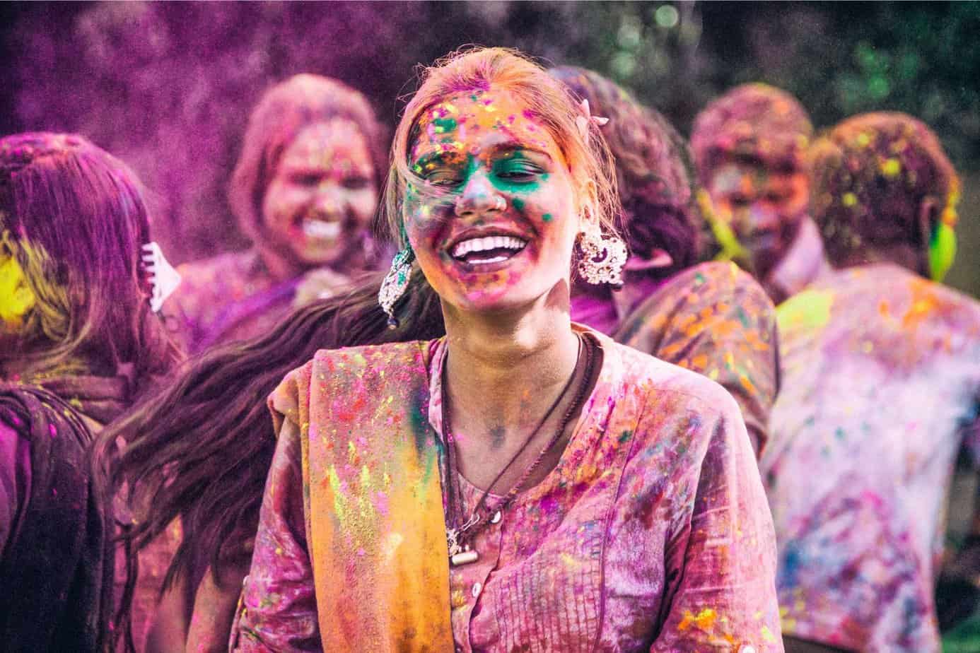 group of people covered in coloured powder playing Holi