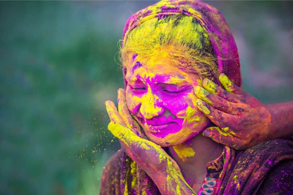 A girl being smeared with yellow colour on her face during Holi