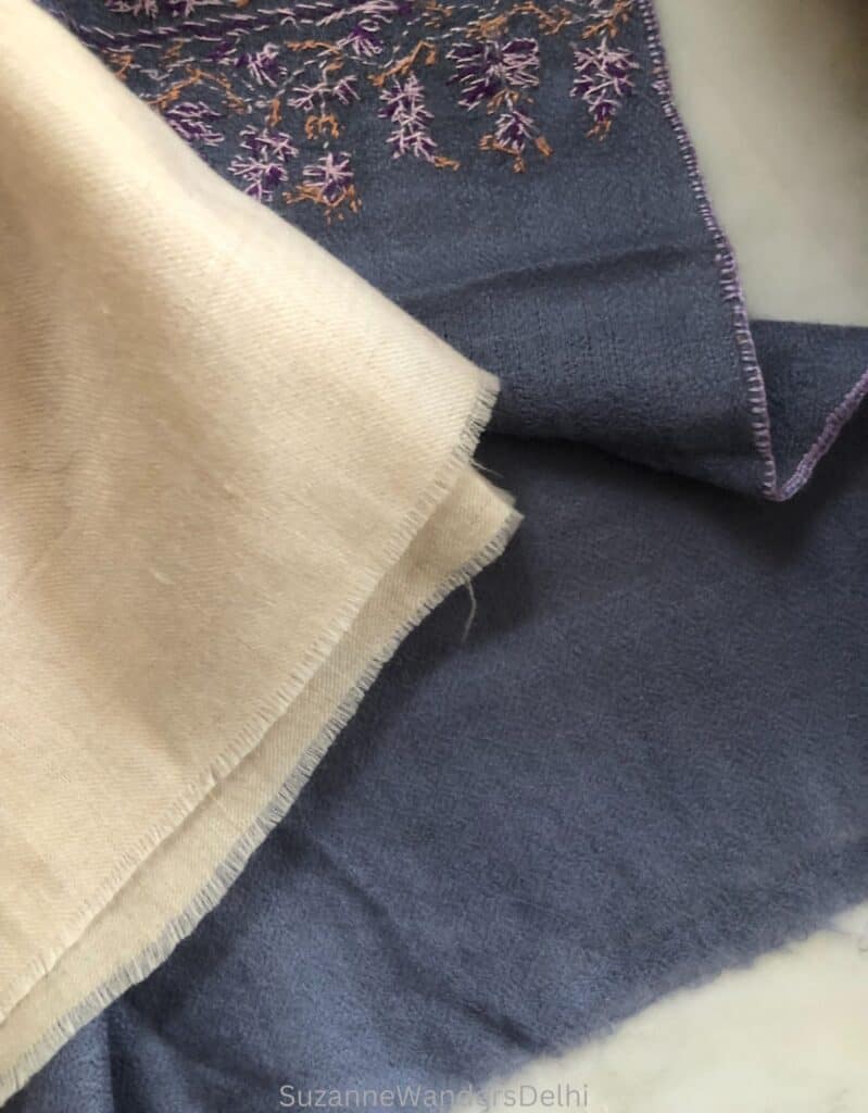 Two pashminas with frayed edges, one cream and one purple with embroidery, this is one way to know if you are buying a real pashmina