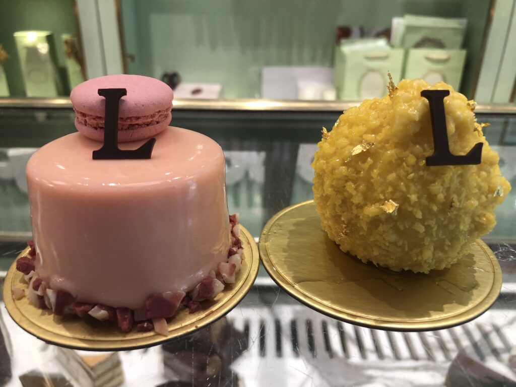 A pink and a yellow pastry both with chocolate Ls in Ladurée, one of the best bakeries in Delhi 