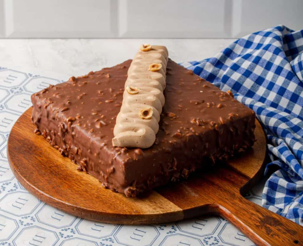 A square chocolate cake on a round wooden board from Cafe Monique, one of the best bakeries in Delhi