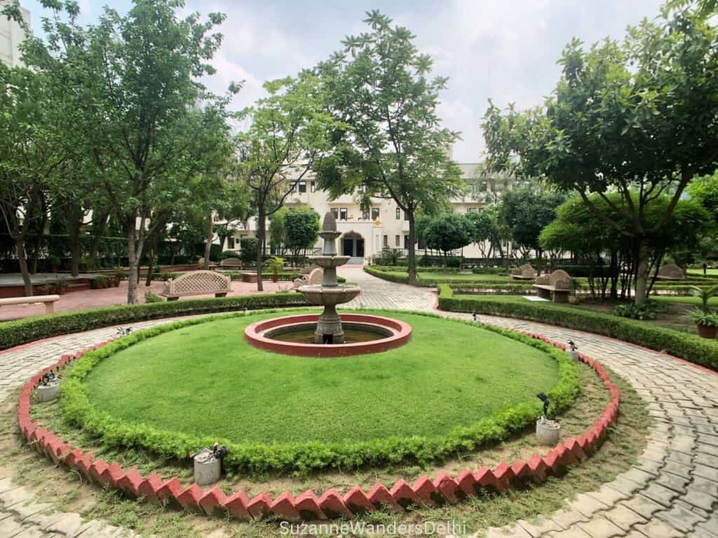 Fountain surrounded by grass and circular pathway in the gardens at Yogoda Satsanga Sakha Ashram, Noida, one of the best ashrams in Delhi