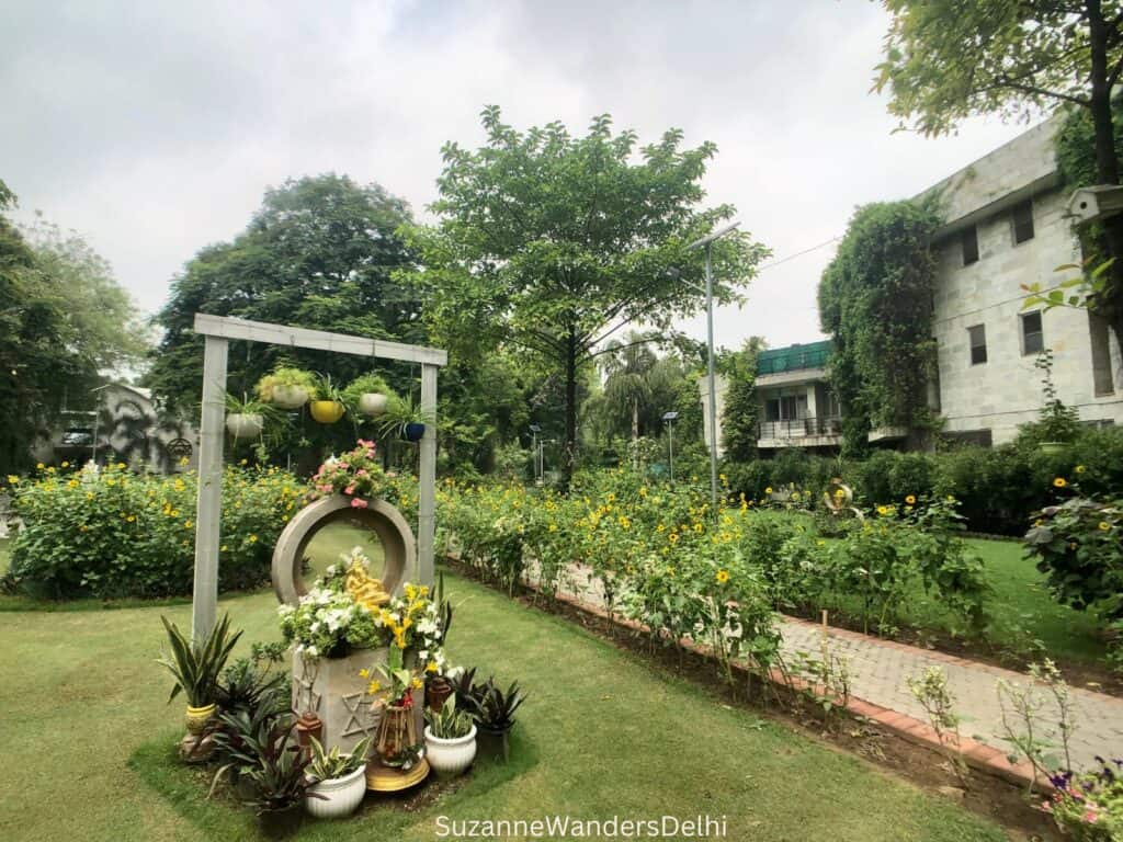 Green lawn with floral display and white building off to the side at Sri Arobindo Ashram Delhi, one of the best ashrams in Delhi