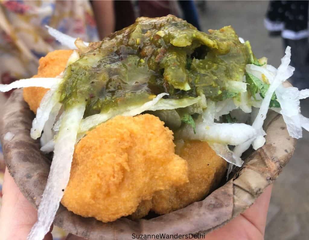 A single serving on ram ladoo piled high with shredded radish and mint chutney, one of the most delicious Delhi street foods