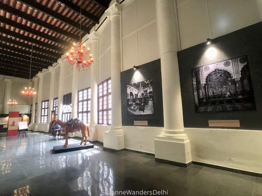 Inside the atrium of the Partition Museum in Delhi with light streaming into the large windows and a display of black and white photographs on the walls