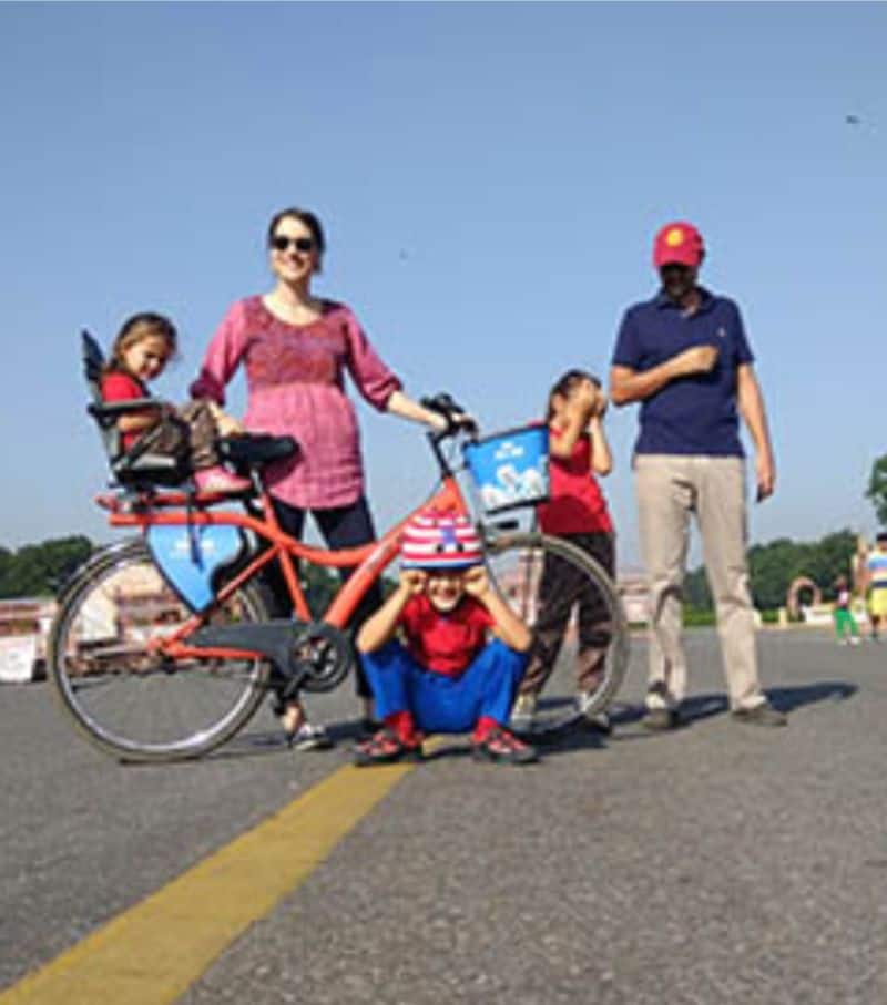 A family of 5 poses sitting and standng around a bike on Rajpath in Delhi
