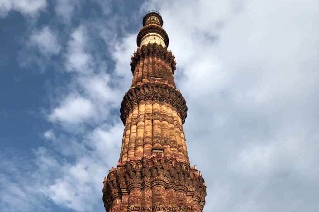 Top portion whowing carvings on Qutab Minar with blue sky in background, usually on most Delhi itineraries