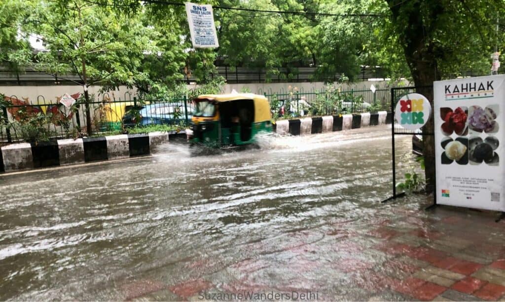 a rickshaw driving through a flooded Delhi street during monsoon 