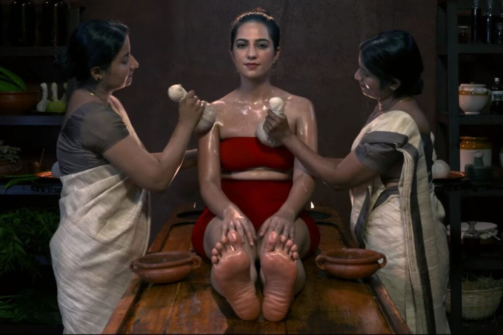 Two massage therapists rubbing poultices on a client during a Pinda Sweda massage in Kerala