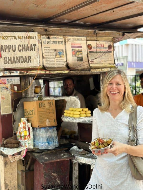 The author outside the Pappu Chaat Bhandar stand holding a serving of fruit chaat