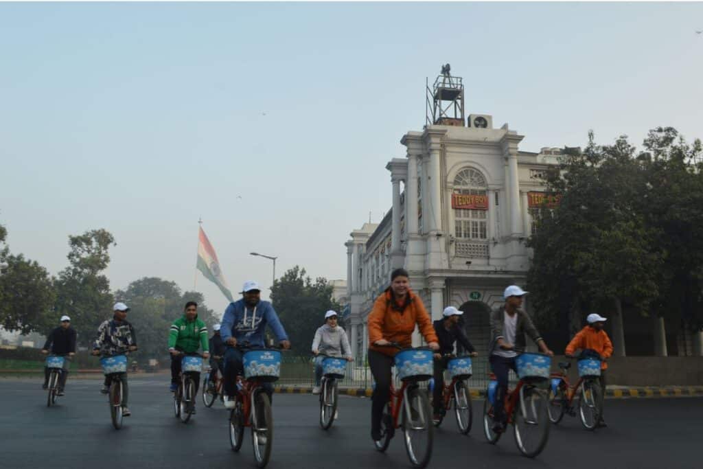 Group of people cycling through Connaught Place early in the morning, a cycling tour is one of the best Delhi sightseeing tours to take