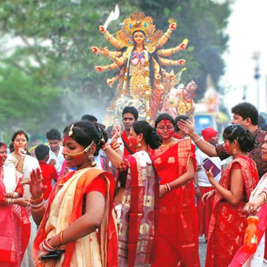 Group of women wearing red and white sarees celebrating Durga Puja outside