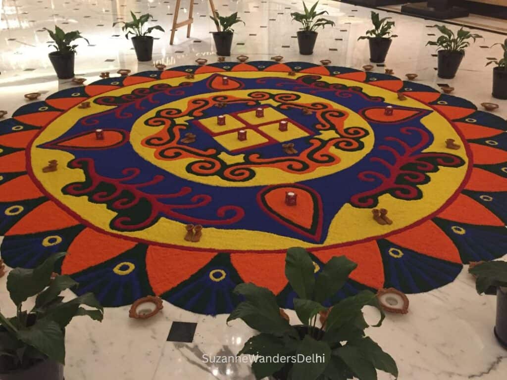 a large colourful rangoli surrounded by small pots of plants on the marble lobby floor of the Shangri-la Eros hotel in Delhi
