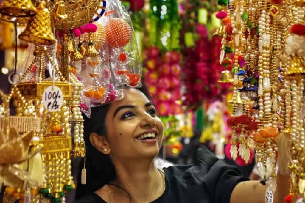 an Indiangril smiling and looking at all gold hanging decor items in Delhi during Diwali