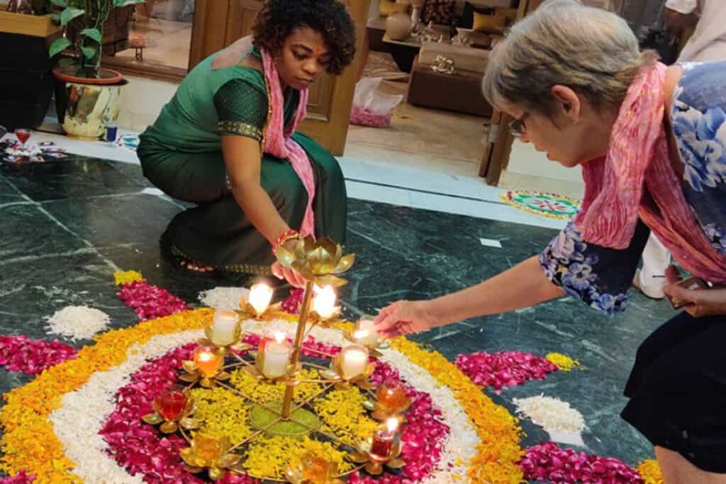 two tourists in Delhi lighting diyas in a rangoli made of flower petals on Diwali