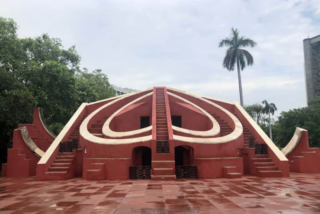 full view of misra yantra instrument flanked by palm tree and green trees at Jantar Mantar in Delhi