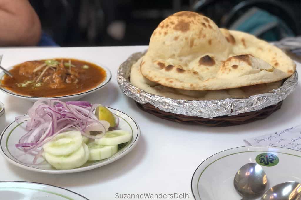 bowl of nihari, salad and tandoor roti on white table at Al Jawahar in Old Delhi