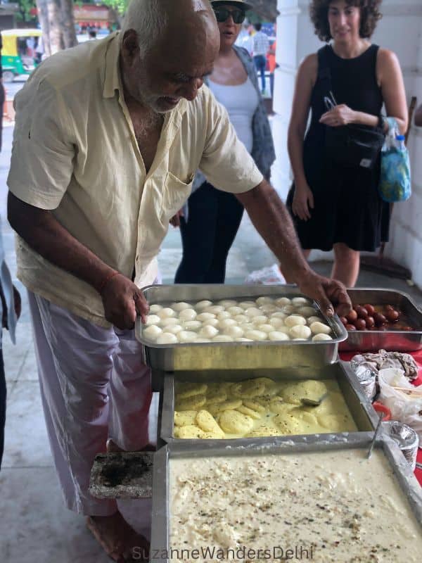 the sweet wala asjusting his trays of milk based Indian sweets in Connaught Place, Delhi
