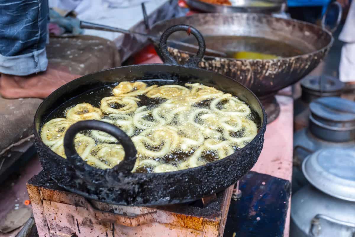 black vat with jalebi cooking over outdoor stove in Old Delhi