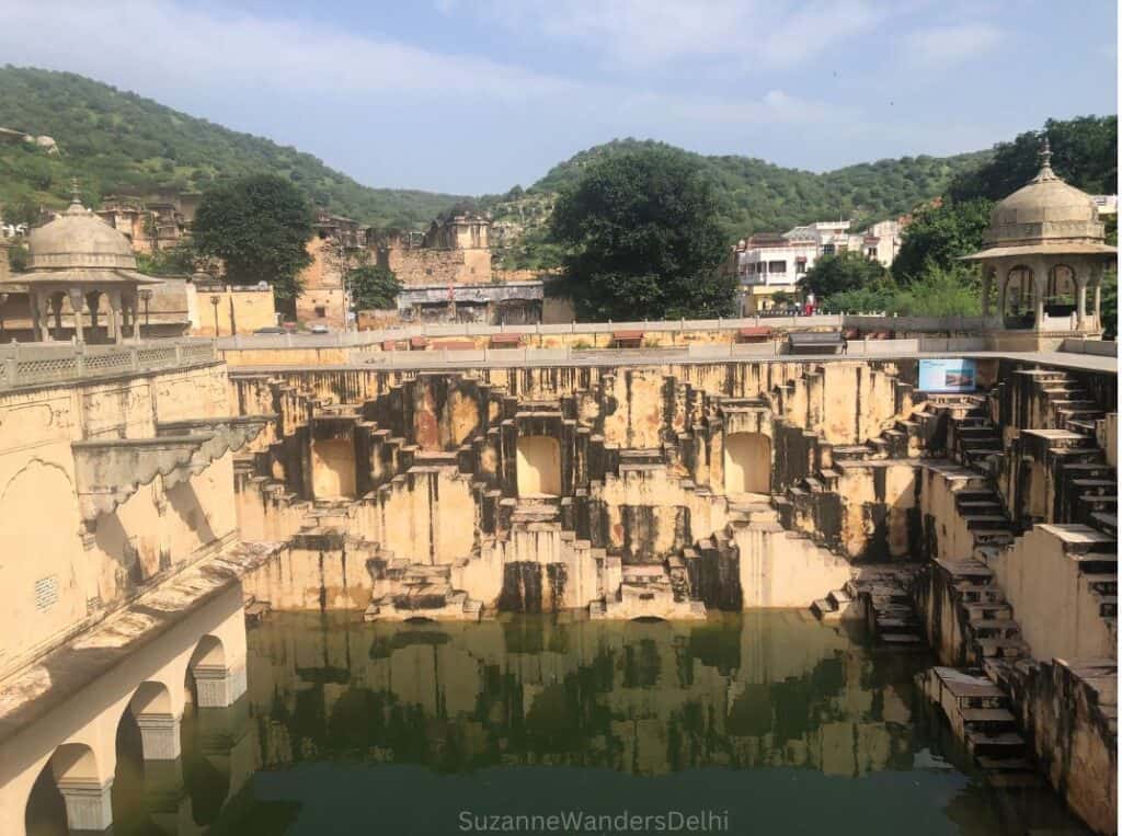 View of Panna Meena ka Kund stepwell in Jaipur with hills in the background, half filled with water